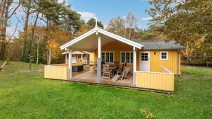 En gul hytte med veranda, et bord og stole.
