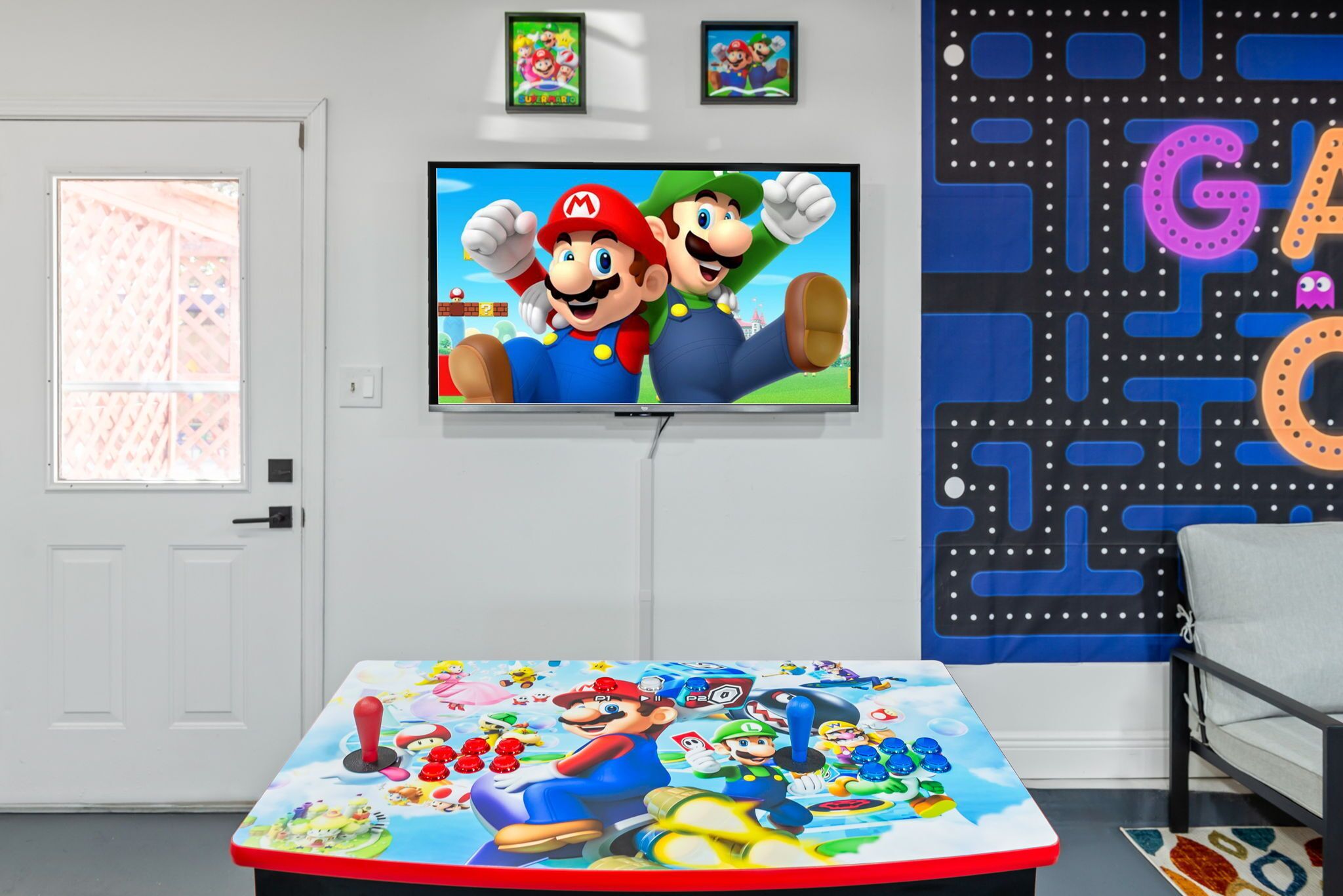 A room with a Nintendo-themed table, a television displaying Mario and Luigi, and a wall with a maze-like design.