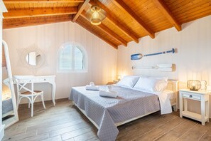 Un dormitorio con cama, mesitas de noche, escritorio, silla, espejo y ventana.