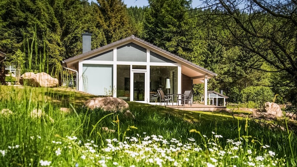 A modern house with a glass facade, a patio with outdoor furniture, and a natural surrounding with trees and grass. - 2 bedroom amazing home in Ruhla (Ruhla)