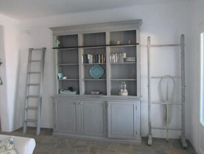 A room with a grey cabinet, a ladder, and a window.