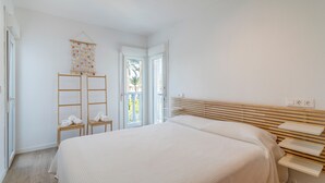 A bedroom with a large bed, wooden headboard, bedside tables, and a view through an open door. - Holiday Home 'Bungalow 213' with Shared Pool, Wi-Fi and Air Conditioning (Santa Pola)