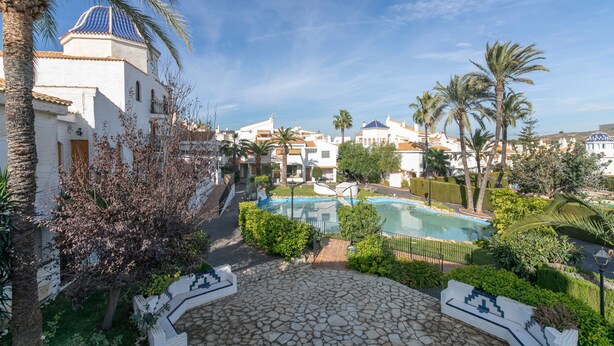 A courtyard with a pool, palm trees, and a white building with a blue dome. - Holiday Home 'Bungalow 213' with Shared Pool, Wi-Fi and Air Conditioning (Santa Pola)