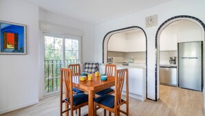 A dining area with a wooden table and chairs, a window with a view, and a kitchen with modern appliances. - Holiday Home 'Bungalow 213' with Shared Pool, Wi-Fi and Air Conditioning (Santa Pola)