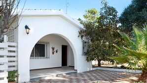 Un bâtiment blanc avec une entrée en arc de cercle, un patio à carreaux et des plantes en pot.