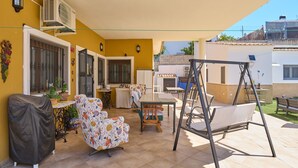 A covered patio with a swing set, a covered grill, and a dining area with a table and chairs. - Holiday Home 'Marisol' with Shared Pool, Wi-Fi & Air Conditioning (Puente Genil)