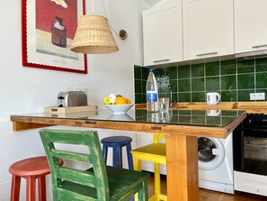 Une cuisine avec une table en bois, un lave-linge et un luminaire suspendu.