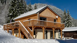 Una cabaña de madera con balcón, rodeada de árboles cubiertos de nieve.