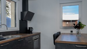 Una cocina moderna con horno integrado, cafetera y ventana con vista a un paisaje nevado.