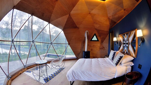 A bedroom with a large window, a bed, a chair, and a wall-mounted lamp. - lobo glamp  (Amanalco de Becerra)