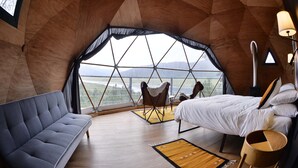 A cozy room with a bed, a sofa, and a view of a landscape through a large window. - lobo glamp  (Amanalco de Becerra)