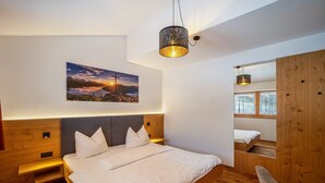 A modern bedroom with a bed, bedside tables, a wall-mounted picture, and a wooden wardrobe.