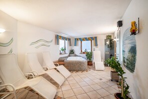 Una habitación con una bañera grande, sillones cómodos y plantas en macetas.