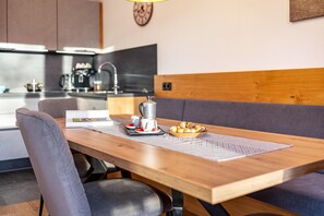 Una cocina moderna con cafetera, una mesa de comedor con posavasos y un sofá.