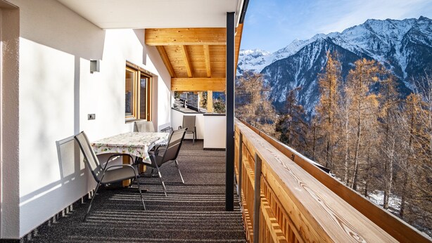 A balcony with a table and chairs, a view of snow-capped mountains, and a wooden ceiling. - Apartment 'Hubertus - Wasserfallspitz' with Mountain View, Private Terrace and Wi-Fi (Sand in Taufers)