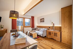 A cozy room with a wooden dining table, a sofa, a small side table, and a cabinet with intricate designs.