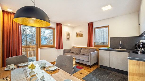 Ein modernes Wohnzimmer mit Esstisch, Sofa und Küchenbereich.