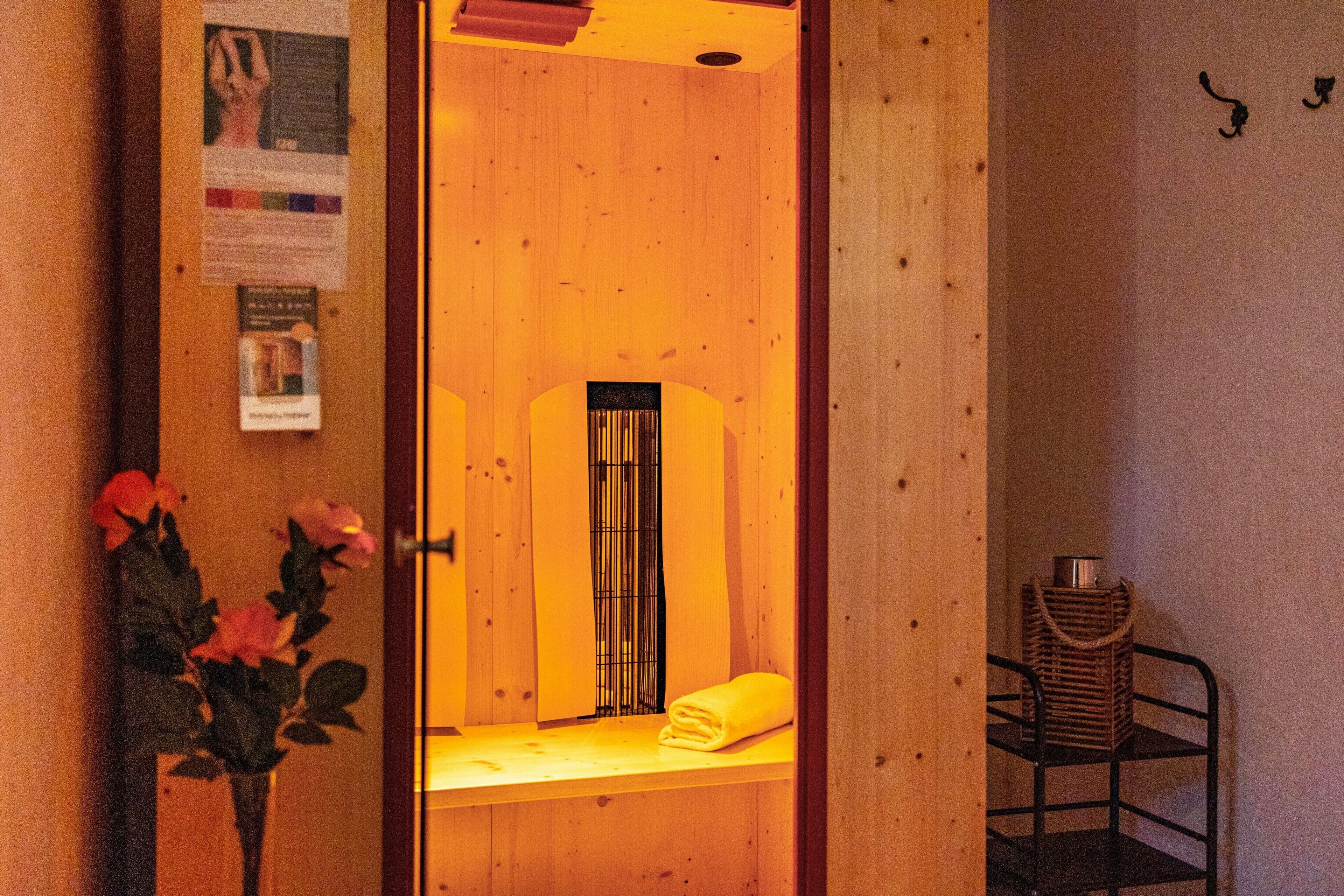 A wooden sauna room with a bench, a towel, and a basket.