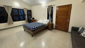 Een slaapkamer met een bed, een bureau, een stoel, een kledingkast en een raam met gordijnen.