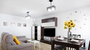 A modern living room with a sofa, dining table, and a flat-screen TV. - Holiday Apartment "Adosado Conil Centro - Families" with Private Terrace (Conil de la Frontera)