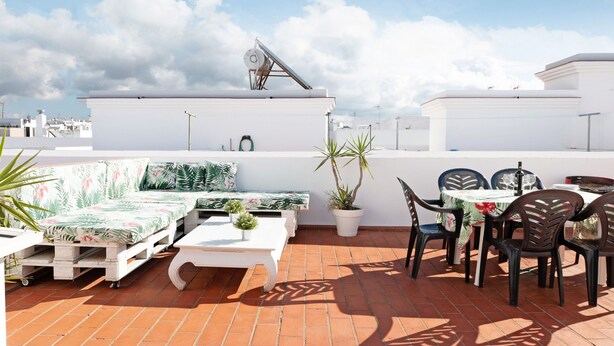 A rooftop terrace with a white sofa, a dining table with chairs, potted plants, and a satellite dish. - Holiday Apartment "Adosado Conil Centro - Families" with Private Terrace (Conil de la Frontera)