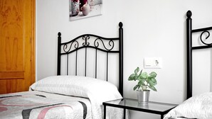 A bedroom with a bed, a bedside table with a plant, a wooden door, and a wall-mounted light switch. - Holiday Apartment "Adosado Conil Centro - Families" with Private Terrace (Conil de la Frontera)