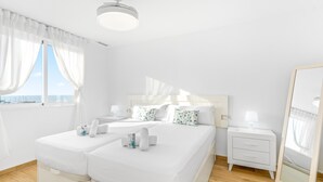 Une chambre d’hôtel avec un grand lit, une table de chevet, une commode, un miroir et une fenêtre avec des rideaux.