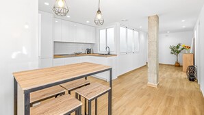 Une cuisine moderne avec des armoires blanches, un plan de travail en bois et des luminaires suspendus.