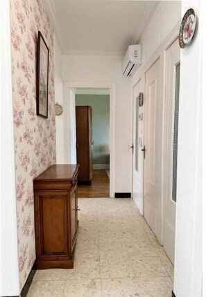 Stylish hallway with a cabinet, door, and air conditioning unit, set against a floral-patterned backdrop.