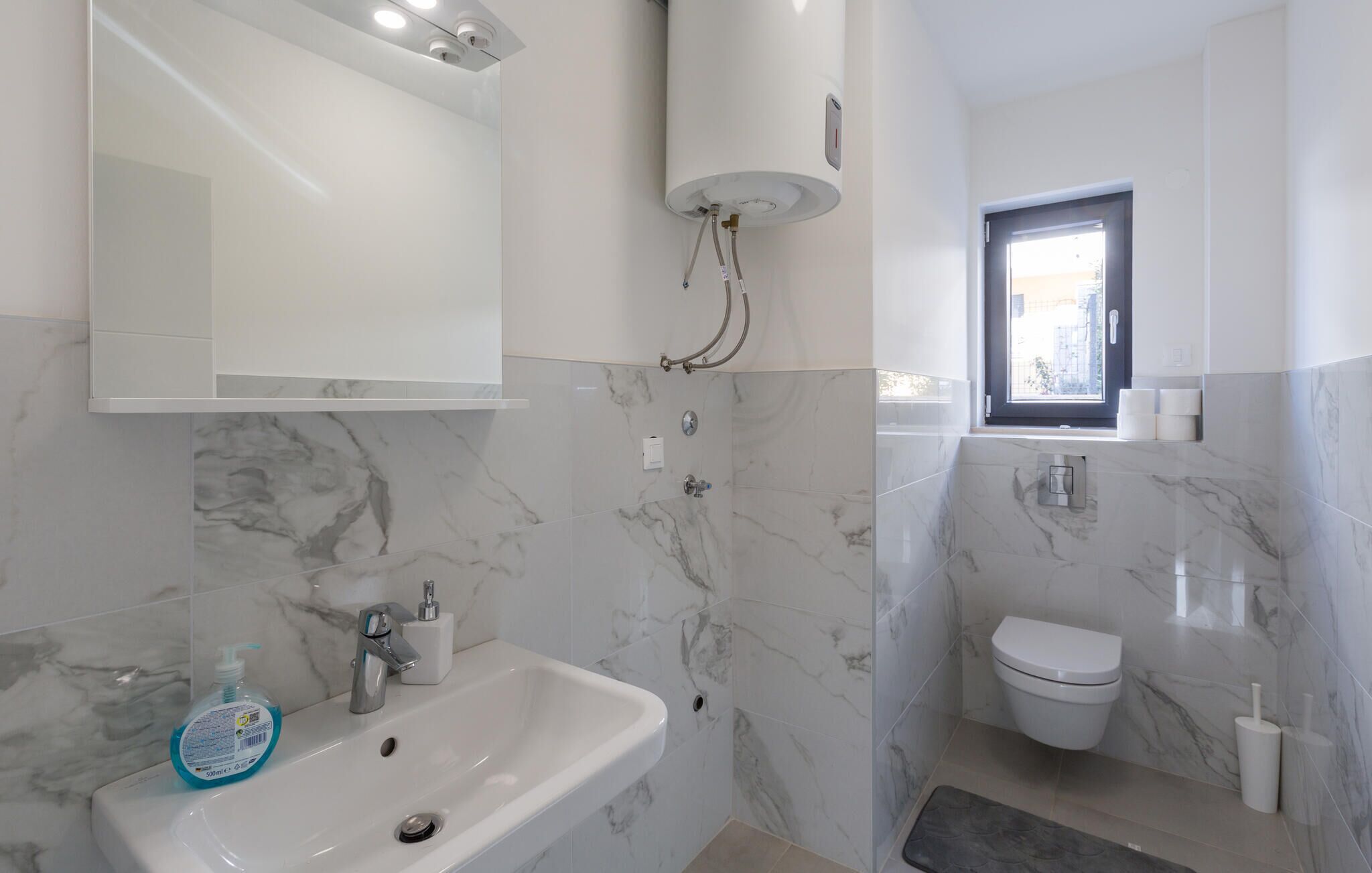 Ein modernes Badezimmer mit Marmorwaschbecken, Toilette und Dusche.