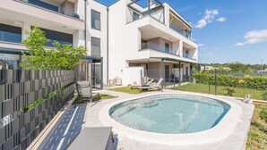 Une maison moderne à deux étages, dotée d’une piscine, d’un patio couvert et d’un jardin clos.