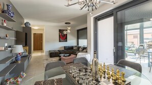 Un salon moderne avec une table basse en verre, un jeu d’échecs et un canapé.