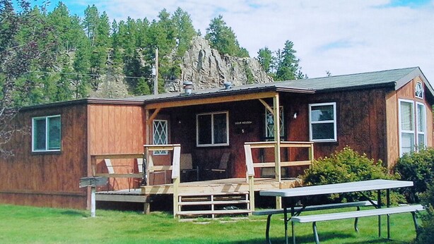 A rustic cabin with a porch, a picnic table, and a small deck area.