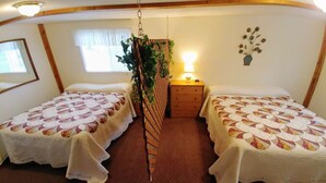 A cozy room with two single beds, a hanging plant, a bedside table with a lamp, and a wall decoration.
