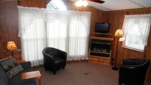 A cozy living room with a fireplace, a television, and two leather chairs.