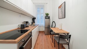 A narrow kitchen with a wooden countertop, stainless steel appliances, and a small dining area with a table and chairs. - 3 Bedrooms - 74sqm - 10 Min. Inner City (Vienna)