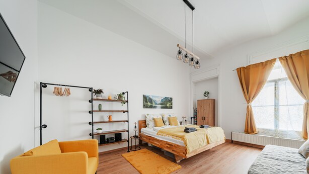 A modern bedroom with a bed, a sofa, a shelf unit, and a window with curtains. - 3 Bedrooms - 74sqm - 10 Min. Inner City (Vienna)