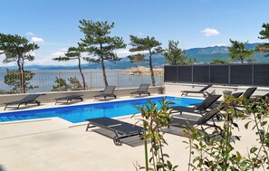 Ein Pool auf dem Dach mit Liegestühlen und Blick auf das Meer.