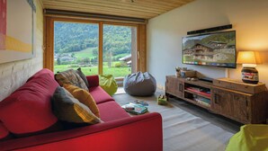Een gezellige woonkamer met een rode bank, een loungestoel en een televisie op een houten kast.