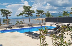 Una piscina sul tetto con lettini e vista sul mare e sulle montagne.