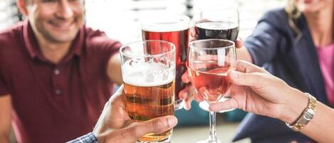 A group of people toasting with glasses of beer in a casual indoor setting.