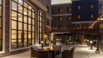 Cortile di un hotel con posti a sedere all'aperto, un braciere e luci decorative.