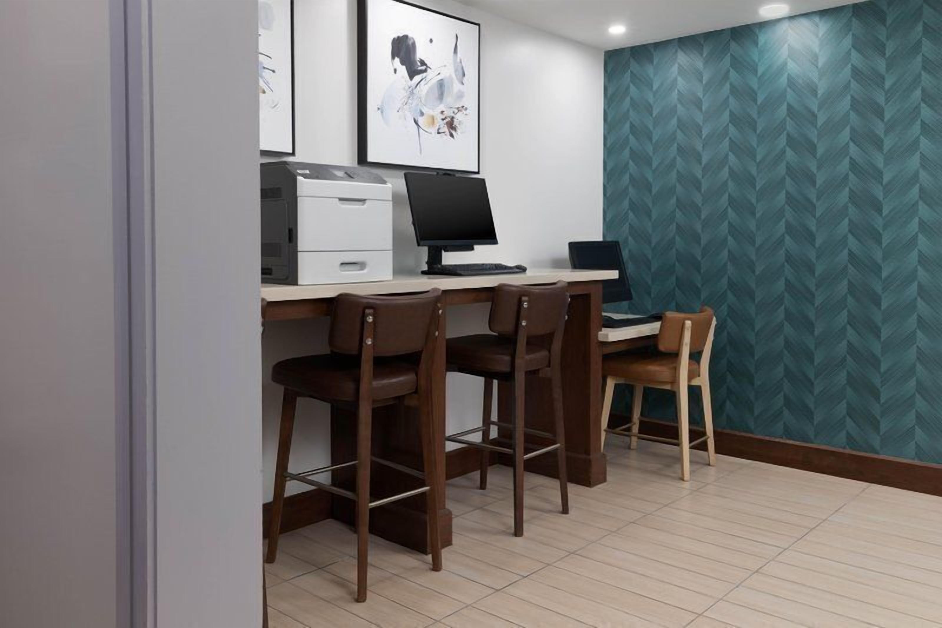 A workspace with a desk, two chairs, a computer, and a printer.