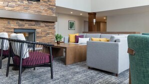 Un espacio lounge moderno con pared de piedra, televisor de pantalla plana, chimenea y un conjunto de sofás y sillones.