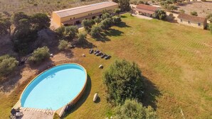 Une grande piscine entourée d’une pelouse, avec quelques arbres et un bâtiment en arrière-plan.