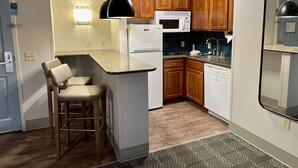 Una cocina compacta con microondas, refrigerador y taburetes de bar.