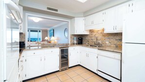 Cozinha moderna com armários brancos, painel de backsplash de tijolos e forno embutido.