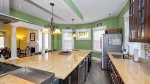 Cocina con una isla grande, electrodomésticos de acero inoxidable y una pared de acento verde.