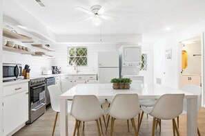 A modern kitchen with white cabinetry, a central island with chairs, and a ceiling fan. - Mystic Woods Trio Branson (Branson)