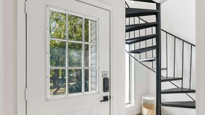 A white door with a window, a black spiral staircase, and a small white stool. - Mystic Woods Trio Branson (Branson)